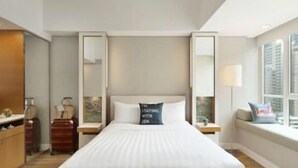 Una camera d'hotel con un letto grande, un comodino, una cassettiera, uno specchio e una finestra con vista.