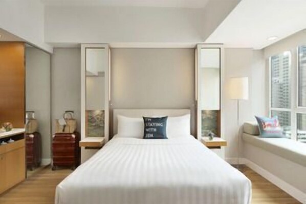 A hotel room with a large bed, a nightstand, a dresser, a mirror, and a window with a view. - Hotel Jen Hong Kong by Shangri-la (Hong Kong Island)