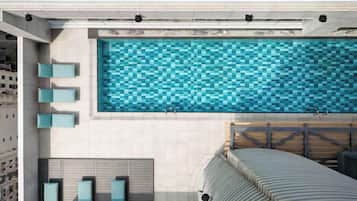 A rooftop pool with a checkered tile pattern, lounge chairs, and a curved roof structure.