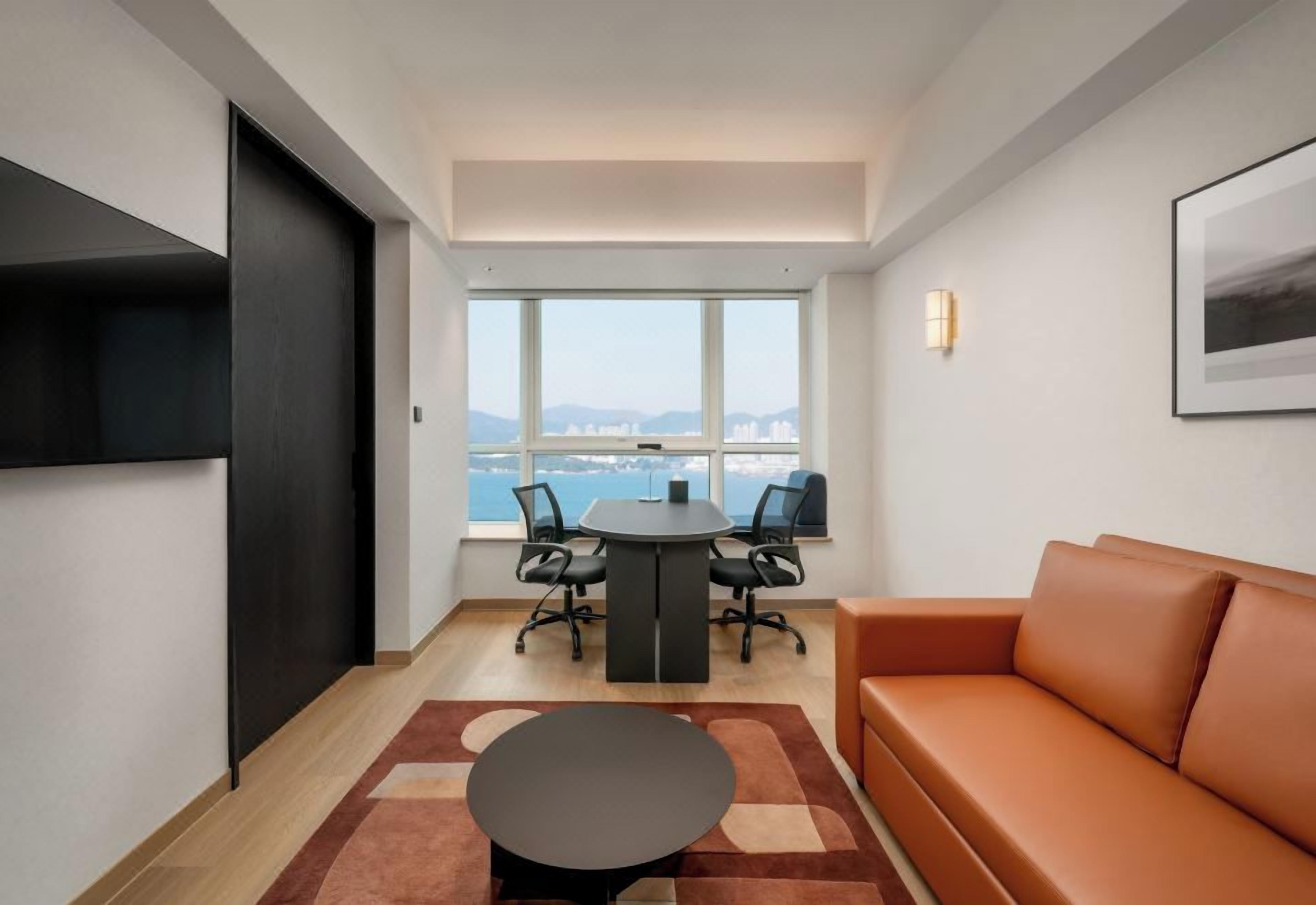 Een moderne kantoorruimte met een ronde tafel, stoelen, een bank en een groot raam met uitzicht op de stad.