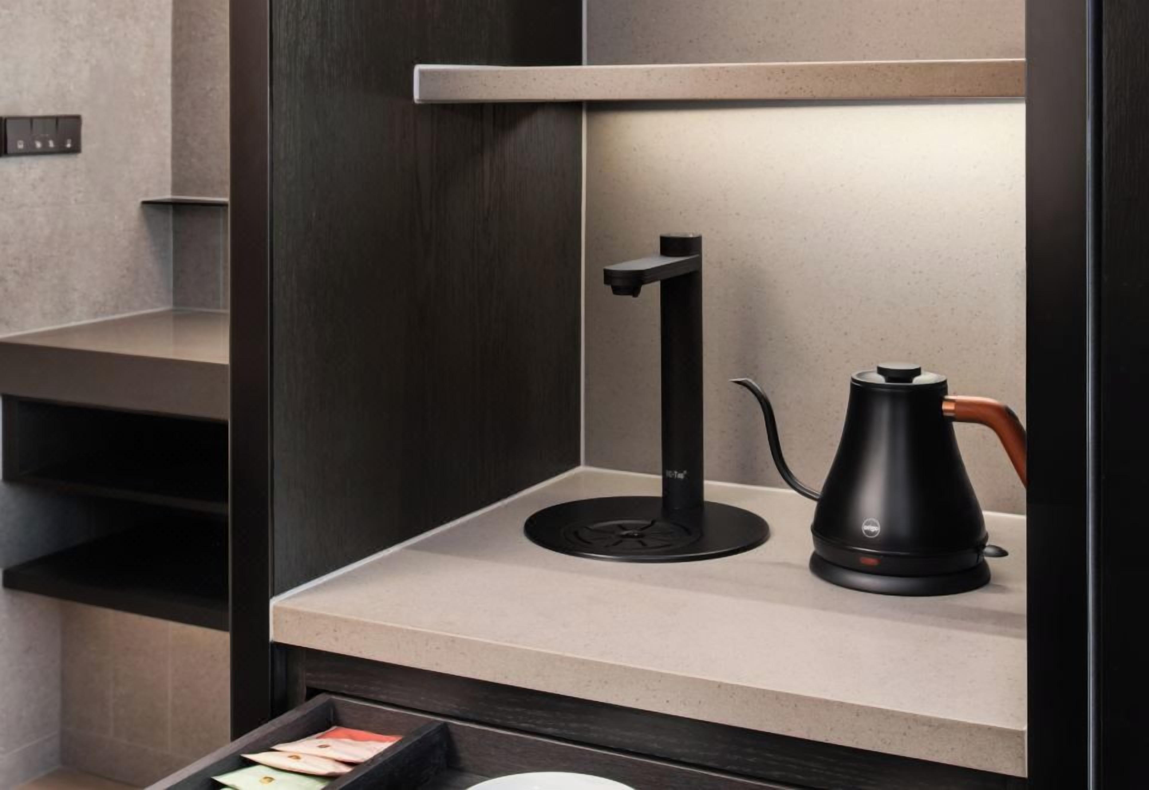 Een moderne keuken met een ingebouwde koffieapparaat en een waterkoker op het aanrecht.