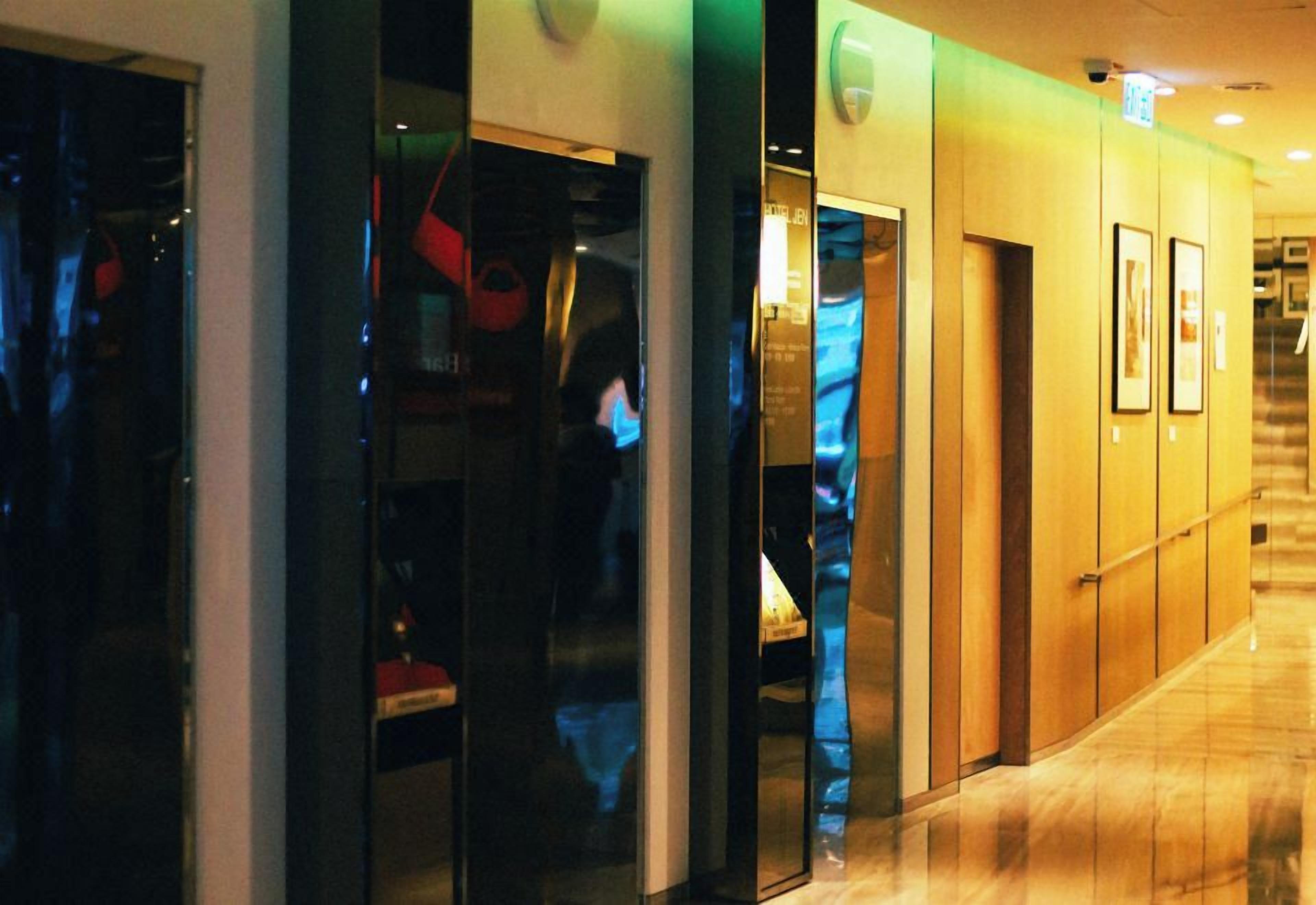 A hotel corridor with glass doors, a staircase, and framed pictures on the wall.