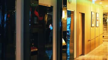 A hotel corridor with glass doors, a staircase, and framed pictures on the wall.