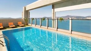 Une piscine sur le toit offrant une vue dégagée sur la mer et les montagnes lointaines.