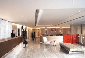 A modern hotel lobby with a reception desk, seating area, and a staircase. - Hotel Jen Hong Kong by Shangri-la (Hong Kong Island)