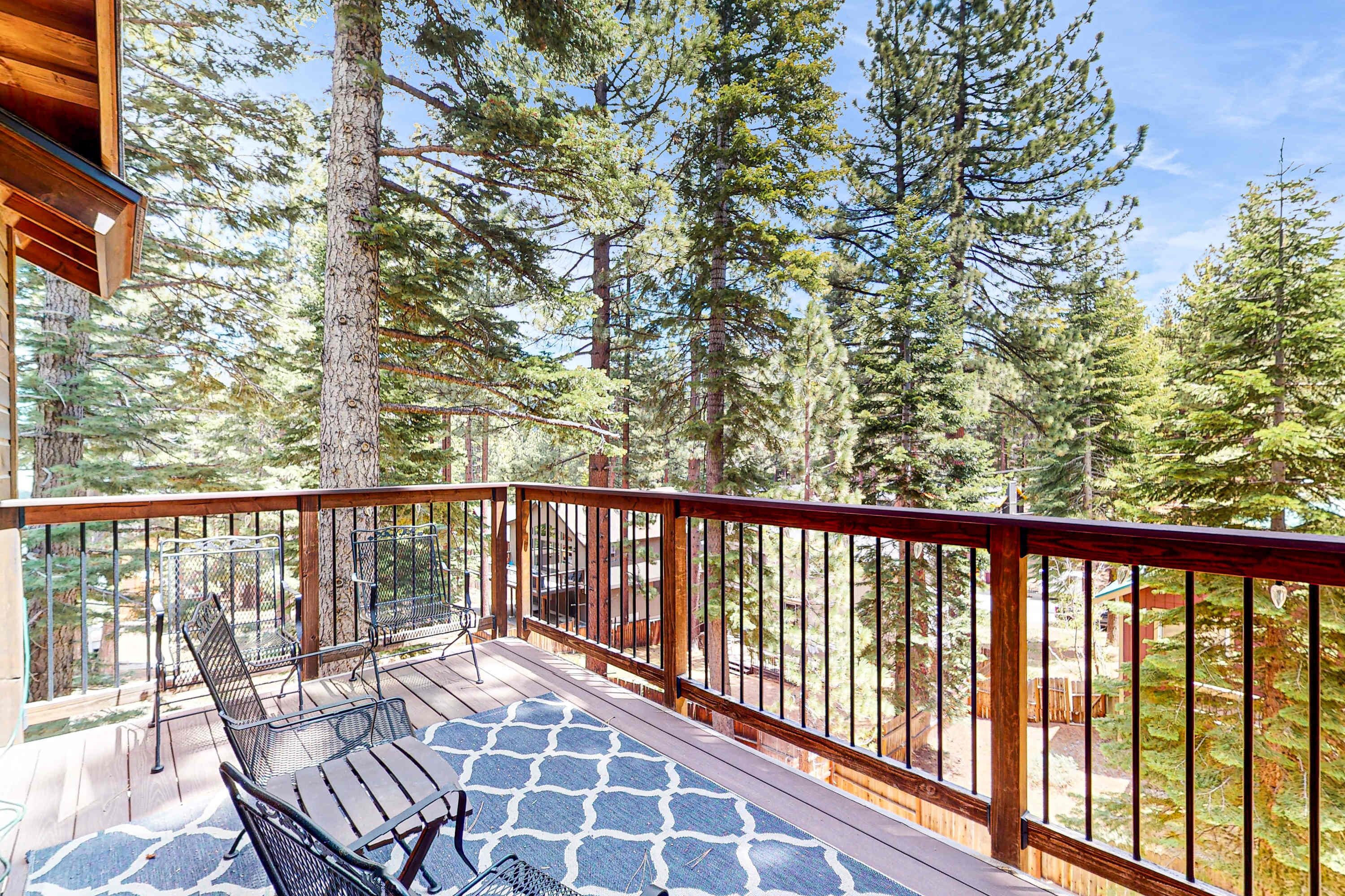Une terrasse en bois avec des rampes en métal, deux chaises en métal et un sol à motifs.