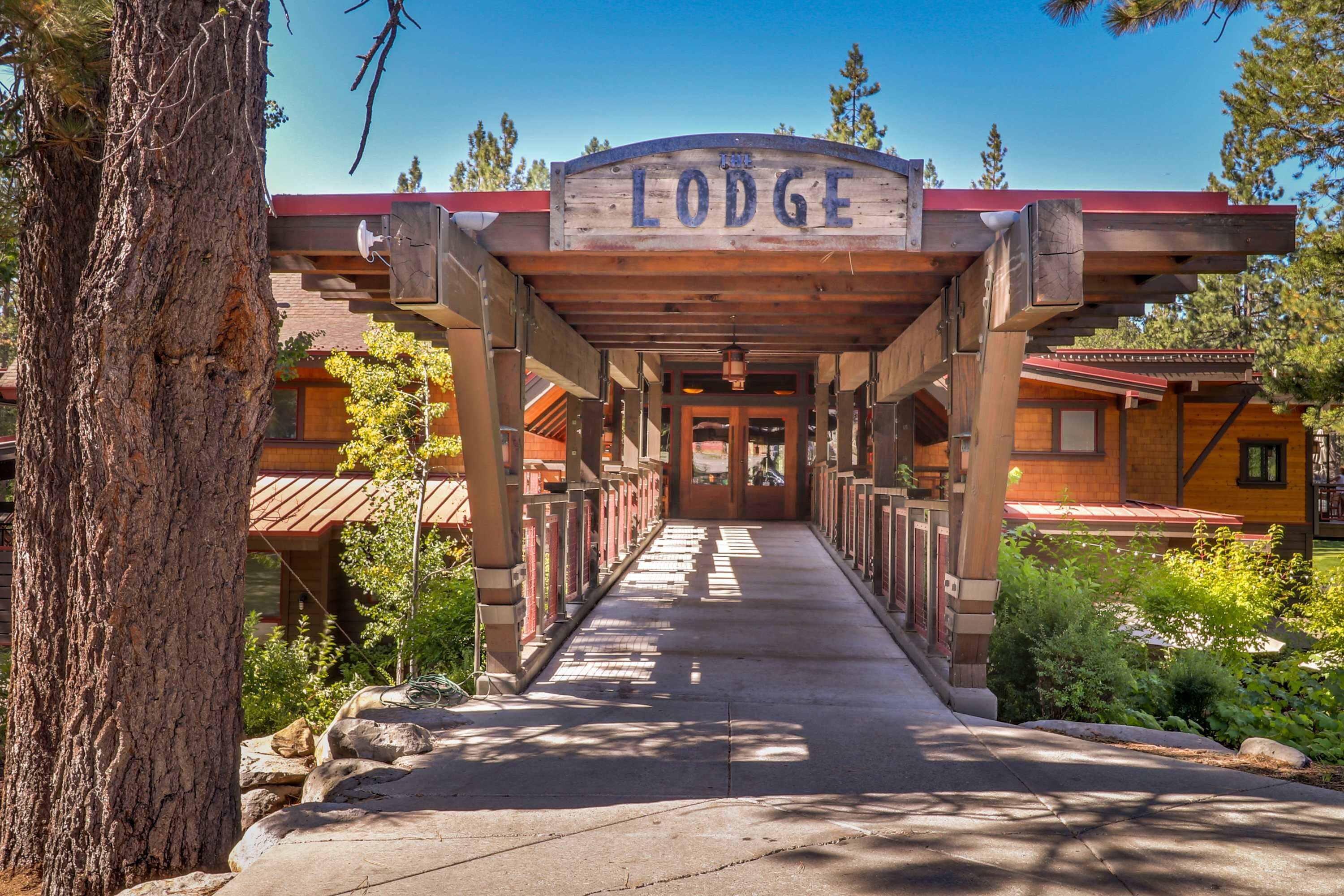 A lodge entrance with a covered walkway leading to the building, surrounded by trees and a clear sky.