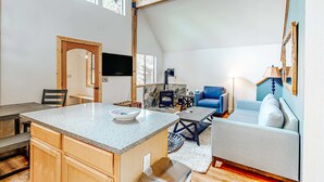 Une cuisine dotée d’un plan de travail en granit, de meubles en bois, d’une cheminée en pierre et d’un coin repas avec une table et des chaises.