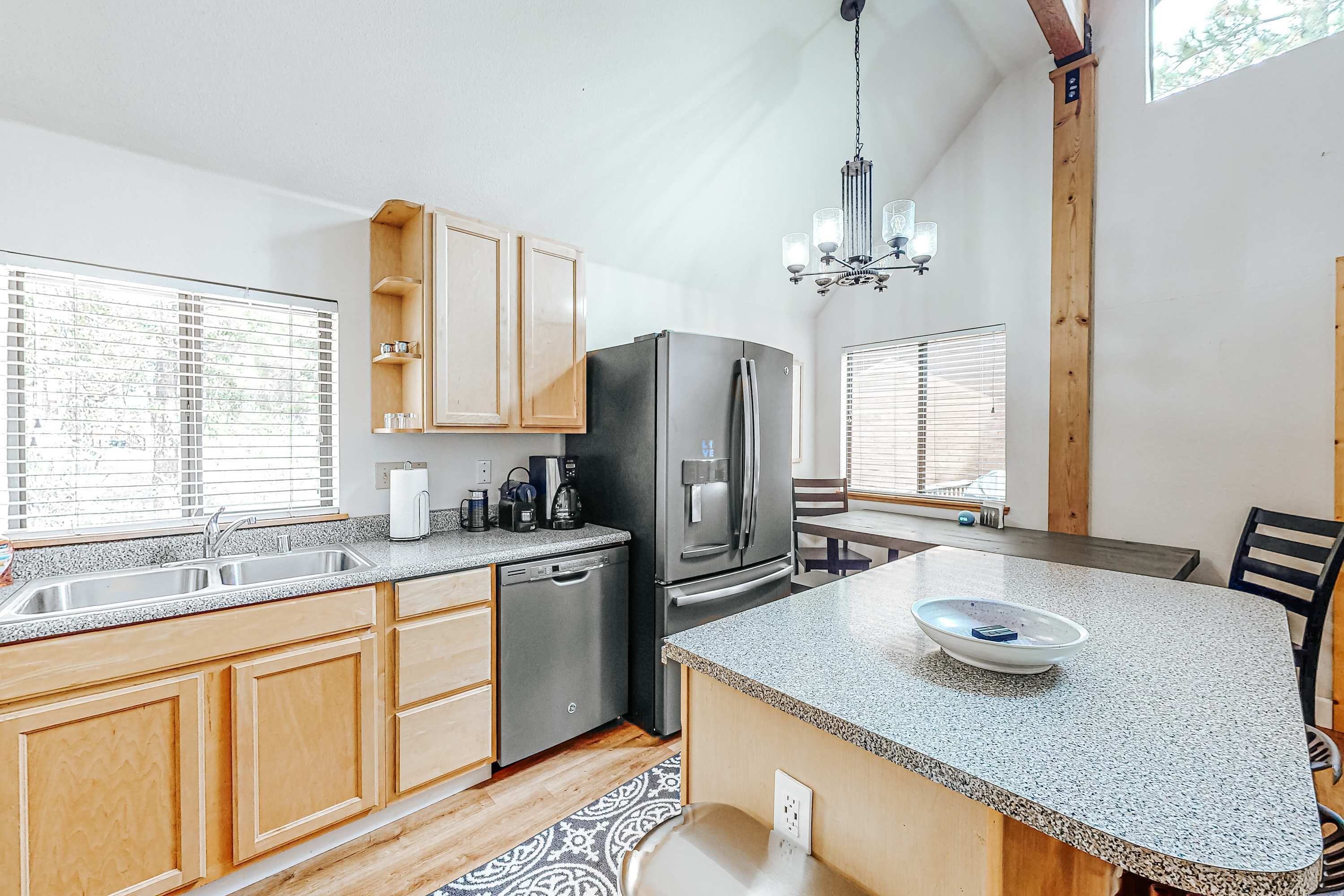 A modern kitchen with wooden cabinets, a stainless steel refrigerator, and a granite countertop.