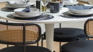 Une table à manger dressée avec des assiettes, des verres et un vase rempli de fleurs.