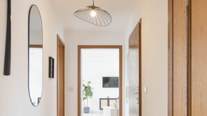 Un couloir avec un banc, un luminaire suspendu et une porte donnant sur une pièce.