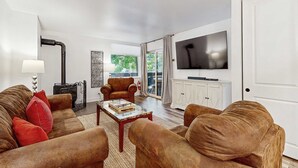 Un salon comprenant un ensemble de canapés, une table basse, une cheminée et un téléviseur fixé au mur.