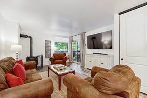 Ein Wohnzimmer mit einer Sofagarnitur, einem Couchtisch, einem Kamin und einem an der Wand befestigten Fernseher.
