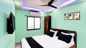 Ein Schlafzimmer mit Bett, Deckenventilator, Klimaanlage, Fenster und Wandbildern.