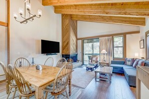 Amplia sala de estar con una mesa de madera para comer, sillas, un sofá y una chimenea.