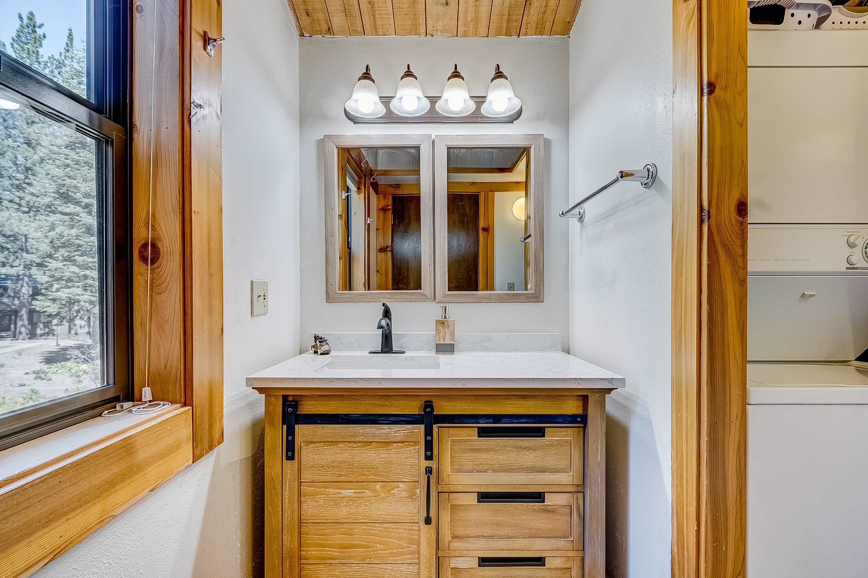 A bathroom with a wooden vanity, a double sink, and a mirror with lights above.