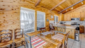 Ein Holzhütten-Interieur mit Essbereich, Küche und großen Fenstern.