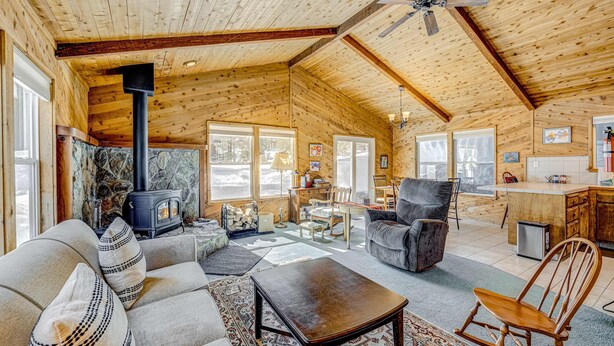 Ein rustikales Blockhaus-Interieur mit Kamin, Sofa, Schaukelstuhl und Küchenzeile.
