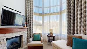 Ein Wohnzimmer mit Kamin, Flachbildfernseher, Sofa und Sessel.