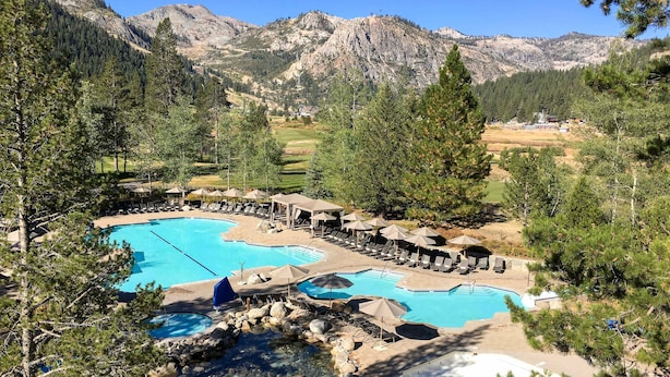 Ein Resort mit mehreren Schwimmbecken, Liegebereichen und einer Bergkulisse.