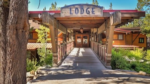 Ein Eingang zu einer Lodge mit einem hölzernen Vordach, einem Schild mit der Aufschrift 'Lodge' und einem Weg, der zum Gebäude führt.