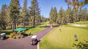 Ein Golfplatz mit Pavillon, Golfwagen und einer Person, die sich zum Schlag vorbereitet.