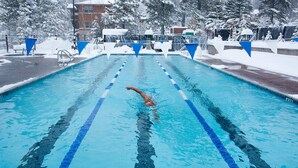 Une piscine avec des couloirs délimités et une personne qui nage.