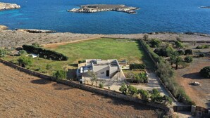 A coastal property with a large open grassy area, a modern house with a flat roof, and a rocky outcrop in the sea. - Beautiful private villa for 12 people with WIFI, A/C, TV and patio (Favignana)