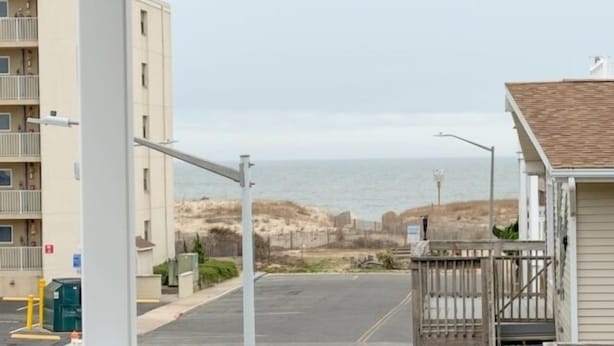 A coastal building with a balcony, a view of the beach, and a parking area. - Ocean Block, 1 Bedroom Condo, WiFi, Washer/Dryer, 2 Blocks to Seacrets (Ocean City)