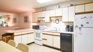 A compact kitchen with white cabinets, a stove, a dishwasher, and a refrigerator. - Ocean Block, 1 Bedroom Condo, WiFi, Washer/Dryer, 2 Blocks to Seacrets (Ocean City)