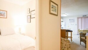 A bedroom with a bed, a nightstand, and a wall-mounted lamp. - Ocean Block, 1 Bedroom Condo, WiFi, Washer/Dryer, 2 Blocks to Seacrets (Ocean City)