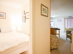 A bedroom with a bed, a nightstand, and a wall-mounted lamp. - Ocean Block, 1 Bedroom Condo, WiFi, Washer/Dryer, 2 Blocks to Seacrets (Ocean City)
