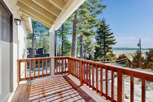 A wooden deck with a railing, overlooking a snowy landscape with trees and a clear sky. - Pristine Modern Condo with Lake Views, Fireplace, Access to Private Beach (Tahoe City)