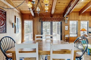 A wooden dining area with a table and chairs, a chandelier, and large windows. - Bright Northstar home on golf course - near ski slopes (Northstar - Truckee)