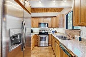 A kitchen with stainless steel appliances, wooden cabinets, granite countertops, and a dishwasher. - Bright Northstar home on golf course - near ski slopes (Northstar - Truckee)