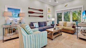 A living room with a sofa, armchairs, a coffee table, and a TV. There are decorative items on the walls and a window with a view. - **THE ELEGANT EGRET @ OLD TOWN** Home & Pool + Last Key White Glove Service... (Key West)