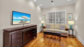 Een woonkamer met een grote flatscreen televisie, een bank, een salontafel en een kast.