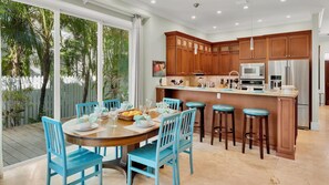 A modern kitchen with wooden cabinets, stainless steel appliances, and a central island with bar stools. - **THE ELEGANT EGRET @ OLD TOWN** Home & Pool + Last Key White Glove Service... (Key West)