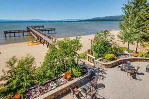 A beachside patio with outdoor seating, a wooden dock, and boats in the water. - Modern home with pool, hot tub, & free WiFi - near the lake & ski lifts (South Lake Tahoe)
