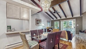 A dining area with a glass table, wicker chairs, and a chandelier. - Updated mountain condo with pool access & wood fireplace - near skiing (Incline Village)