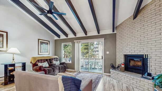 A living room with a fireplace, a sofa, a coffee table, and a ceiling fan. - Updated mountain condo with pool access & wood fireplace - near skiing (Incline Village)