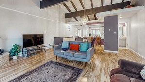 A spacious living area with a sofa, TV, and a dining area in the background. - Updated mountain condo with pool access & wood fireplace - near skiing (Incline Village)
