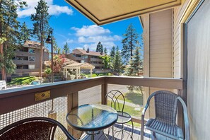 A balcony with a table and chairs, overlooking a residential area with houses and trees.