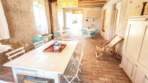 A rustic interior with a white table and chairs, a brick floor, and exposed wooden beams. - Stunning private villa for 11 guests with WIFI, private pool, A/C, TV and patio (Montalto Delle Marche)