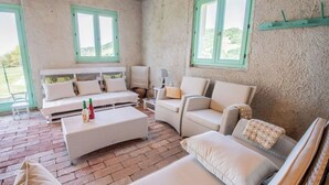 A room with a sofa, armchairs, a small table, and two windows. - Stunning private villa for 11 guests with WIFI, private pool, A/C, TV and patio (Montalto Delle Marche)