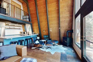 Ein gemütliches Blockhaus-Interieur mit Schlafzimmer im oberen Bereich, einer Küchenzeile und einer Sitzecke mit Kamin.