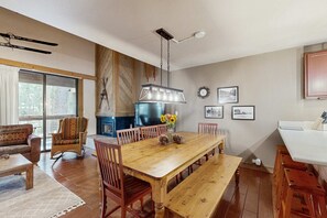A dining area with a wooden table, chairs, a bench, a hanging light fixture, and a fireplace. - Secluded Getaway with Free WiFi plus a Rec Center with a Pool & Hot Tub (Northstar - Truckee)
