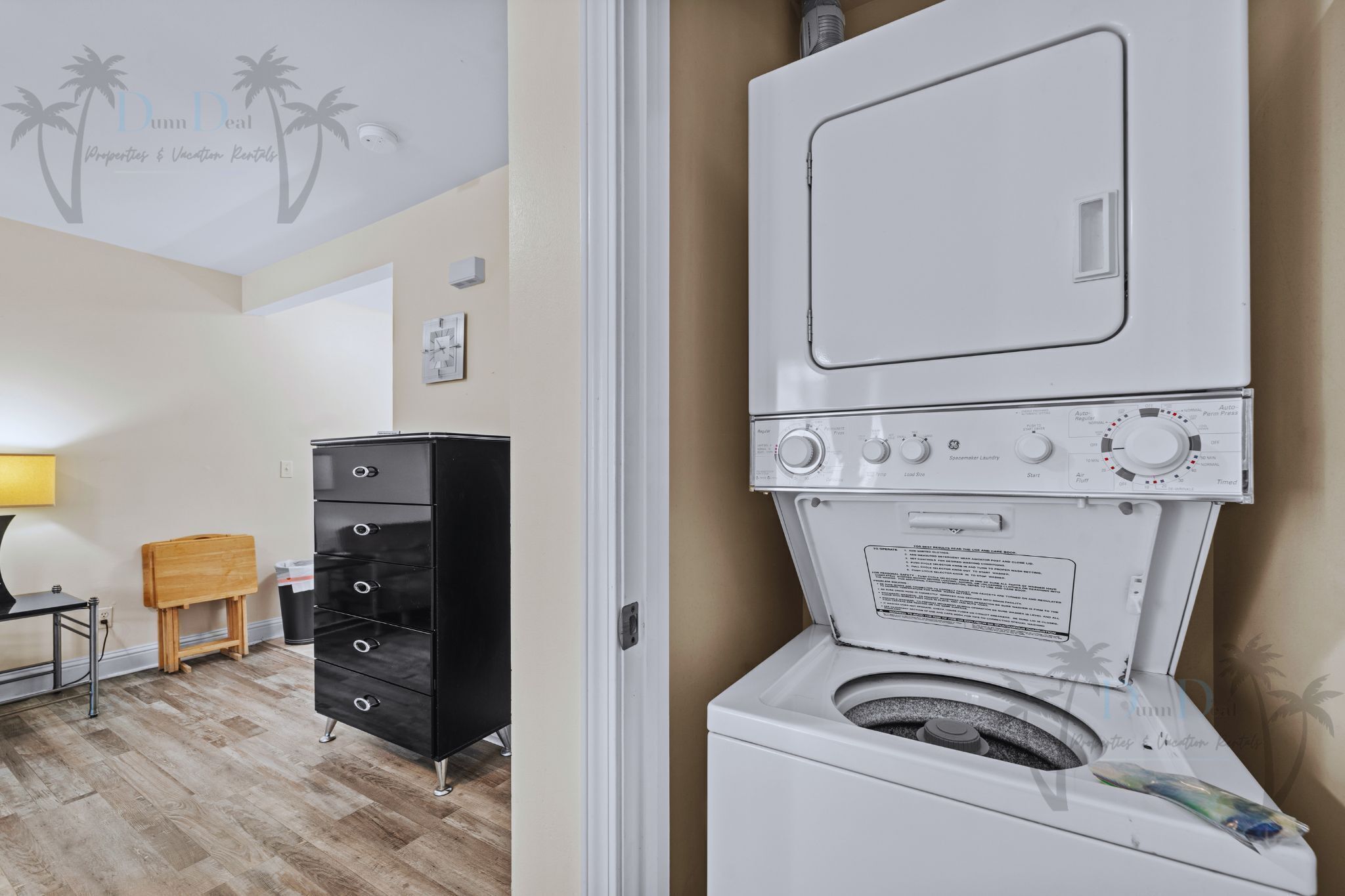 A laundry area with a washing machine, a black cabinet, and a wooden stool.