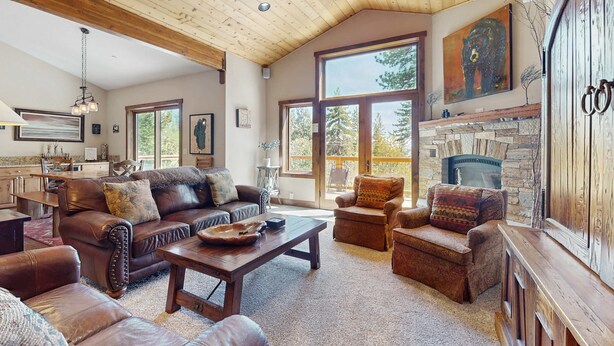 Un salón espacioso con techo alto, sofás de cuero, chimenea y ventanas grandes.
