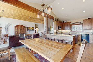 A spacious kitchen with wooden cabinets, a large island, and a dining area with benches. - Mountain home with  fireplace, partial lake views from deck & hot tub (Tahoe City)